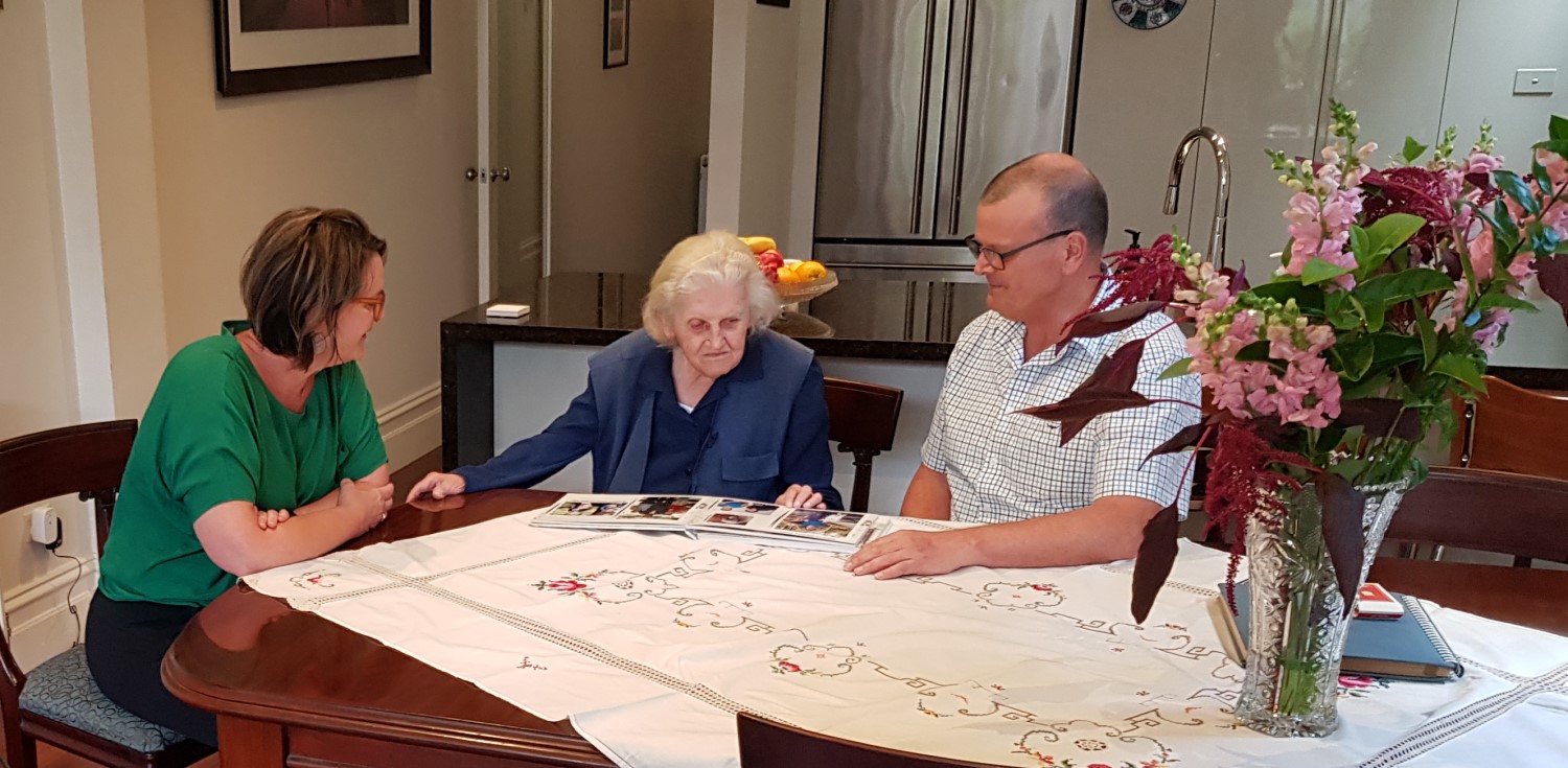A family sitting together at a kitchen table looking through a photo album
